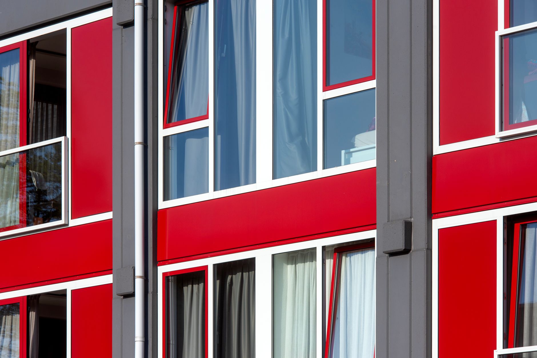 White window frames with tilt sashes set into a red and grey building facade